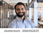 Happy smiling bearded indian business man small business owner, company leader or sales manager, male hispanic ceo executive, successful lawyer looking at camera standing in office, headshot portrait.