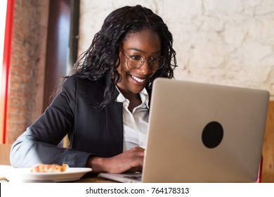 Happy, smiling beautiful african american woman in prescription glasses, business startup freelancer or designer works on laptop in coworking hub, empowered female with technology