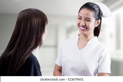 Happy And Smiling Beautiful Asian Nurse Talking To A Lady Patient.