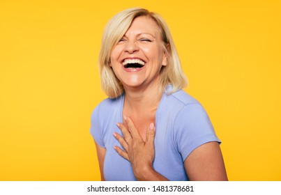 Happy smiling beautiful cute lovely blonde senior woman with beauty clean skin in casual wear isolated on yellow background. Healthcare and cosmetology concepts. Pensioner and mature people
