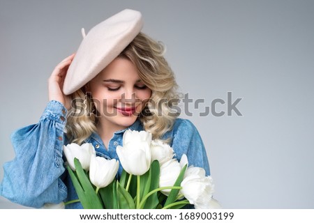 Happy smiling beautiful fashionable  blonde lady wearing beret, holding spring bouquet of white tulips. Close up portrait. Copy, empty space for text