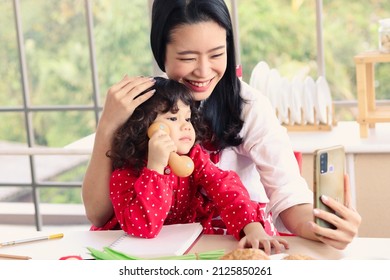 Happy Smiling Beautiful Young Asian Mom Holding Mobile Phone Taking Selfie With Her Little Adorable Child Daughter Girl, Mother Enjoy Spending Special Time With Her Kid. Love And Warmth Family Concept