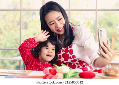 Happy Smiling Beautiful Young Asian Mom Holding Mobile Phone Taking Selfie With Her Little Adorable Child Daughter Girl, Mother Enjoy Spending Special Time With Her Kid. Love And Warmth Family Concept