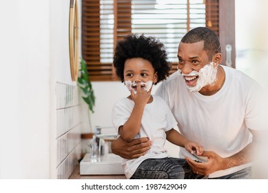 Happy Smiling Black African American Father and little son with shaving foam on their faces having fun and looking away. - Powered by Shutterstock