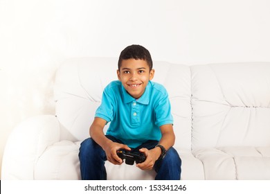 Happy Smiling Black Boy Playing Video Games Holding Game Controller Sitting On The Coach In Living Room