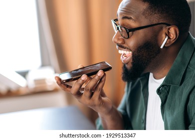 Happy Smiling Black Guy, Holding And Using Cell Phone, Speaking With Friend Or Colleague Speakerphone, Sitting At Home Or Office, Record Voice Message