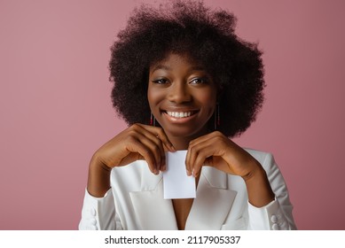 Happy Smiling Black Woman, Model Wearing Elegant Jewelry, Classic Shirt, Holding Small White Paper Bag, Box, Posing In Studio, On Pink Background. Copy, Empty Space For Text
