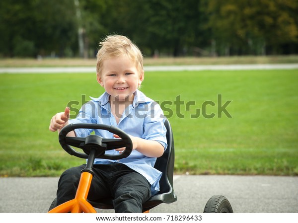 Happy smiling boy driving toy car.and having fun,\
outdoors. Kid with toy car and thumb up plays outside, outdoor.\
Education for kids. driving instruction. Close up of cute boy\
portrait. 