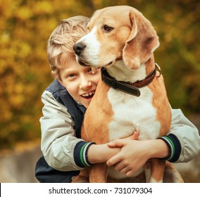 Happy smiling boy hugs his best freind beagle dog 