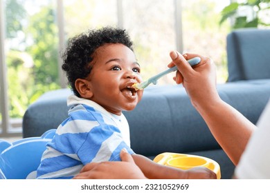 Happy smiling boy with mom while eating in the living room at home. Preschool child development, food menu for 1 year olds - Powered by Shutterstock