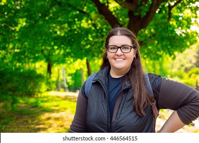Happy smiling brunette plus size woman with glasses at the green park nice spring summer day in the sunlight - peaceful and relax