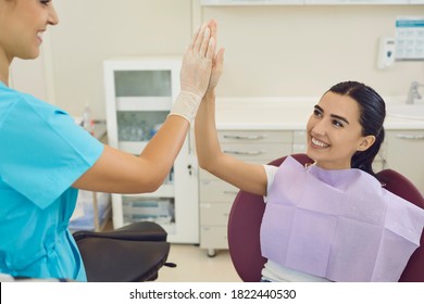 Happy smiling brunette woman happy with the result of dental treatment and gives five to her dentist sitting in a chair in a modern dental clinic. Dentistry, medicine and health care concept. - Powered by Shutterstock