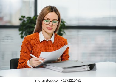 Happy smiling business woman at work talking on phone, sitting at her working place in office, copy space