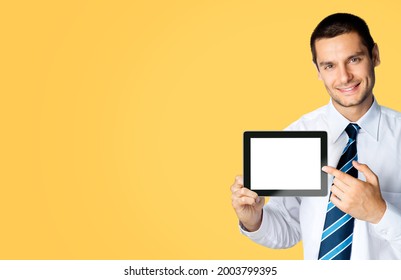 Happy Smiling Businessman In White Shirt And Tie, Showing Pointing Tablet Pc, Touchpad, With Copy Space Area For Text Or Slogan, Over Orange Yellow Colour Background. Confident Business Man At Studio.