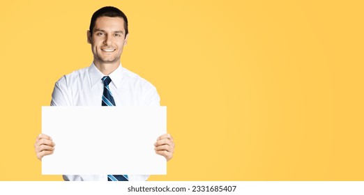 Happy smiling businessman in white shirt and tie, showing blank signboard with copy space area for text or sign, orange yellow colour background. Confident business man holding paper board at studio. - Powered by Shutterstock