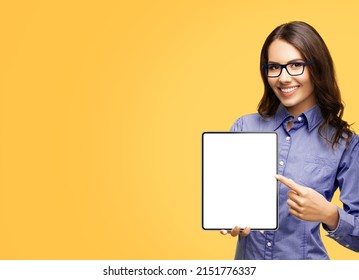 Happy smiling businesswoman in eye glasses spectacles showing touchpad tablet pc, with white screen copy space text area for advertising or slogan sign, isolated over yellow background. Business woman