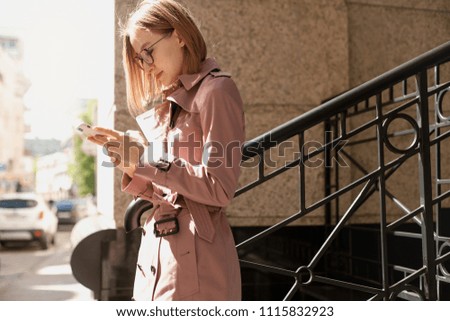 Happy smiling businesswoman using modern smartphone device, successful female entrepreneur using cellphone wireless connection walking along the street, young woman browsing mobile phone outside