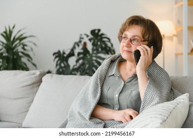 Happy smiling caucasian old senior elderly woman lady grandmother talking communicating with friends, grandchildren, colleagues on cellphone, smart phone online at home - Powered by Shutterstock