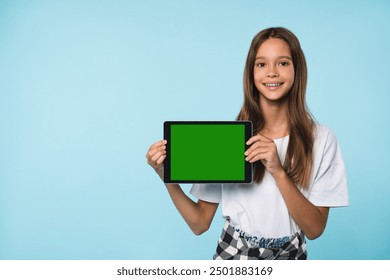 Happy smiling caucasian schoolgirl teenager child pupil student holding digital tablet showing blank screen with advert place mockup isolated in blue background - Powered by Shutterstock