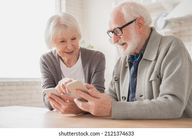 Happy smiling caucasian senior elderly couple grandparents spouses using smart phones cellphones together, surfing social media, e-banking, e-commerce at home kitchen, online shopping on application - Powered by Shutterstock