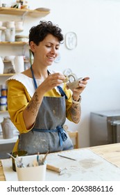 Happy smiling ceramist shape cap for handmade potter jug in workshop. Cheerful woman in apron enjoy art craftsmanship classes in studio. Sculptor work on handicraft tableware for retail store business