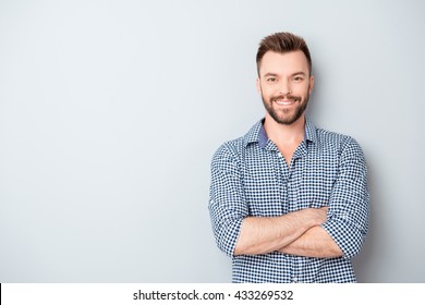 Happy smiling cheerful guy with crossed hands on gray background