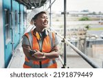 A happy, smiling and cheerful young black woman or senior construction industry worker standing at a building site. A professional female employee working at housing or property development location