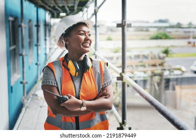 A happy, smiling and cheerful young black woman or senior construction industry worker standing at a building site. A professional female employee working at housing or property development location - Shutterstock ID 2191879449
