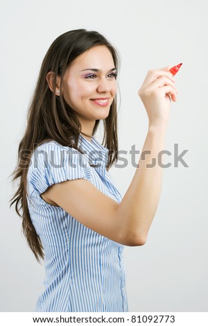 Happy smiling cheerful young business woman writing or drawing on screen with red marker, isolated on white background