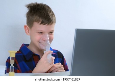 Happy smiling child boy is breathing in mask using nebulizer for inhalation at home watching laptop. Fibrosis, covid-19, asthma, copd. Treatment, cure and procedure. Using inhaler for therapy.