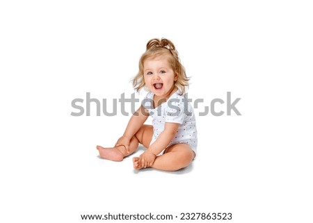 Happy, smiling child. Little baby girl, toddler sitting on floor and cheerfully laughing against white studio background. Concept of childhood, motherhood, care, life, birth. Copy space for ad