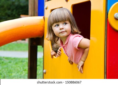 Happy smiling child   in small house on playground 