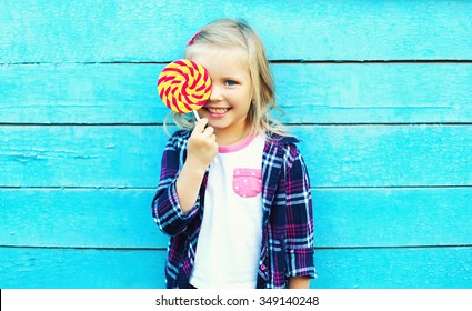 Happy Smiling Child With Sweet Lollipop Having Fun Over Colorful Blue Background