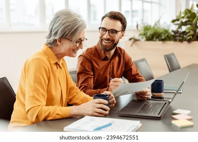 Happy smiling colleagues using laptop talking, sharing ideas, planning startup, drinking coffee working together in modern office. Meeting, teamwork, successful business - Powered by Shutterstock