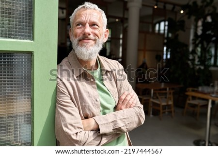 Happy smiling confident european middle aged older adult man small local business owner standing outside own cafe looking away and dreaming. Old senior entrepreneur portrait. Entrepreneurship