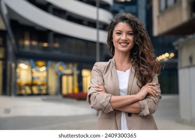 Happy smiling confident female leader businesswoman standing outside the modern office workplace looking at camera with arms crossed. Business successful executive concept. Portrait. - Powered by Shutterstock