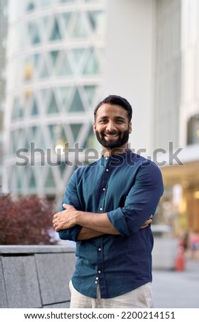 Happy smiling confident rich successful indian business man leader, successful eastern professional businessman crossing arms looking at camera posing outside in big urban city, vertical portrait.