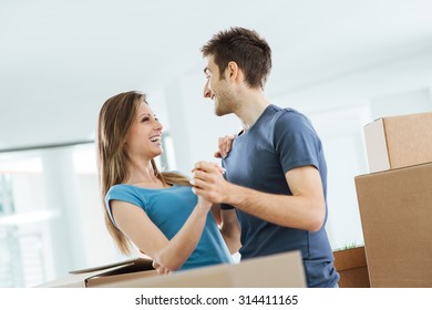 Happy Smiling Couple Dancing In Their Beautiful New House Surrounded By Carton Boxes