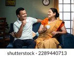 Happy smiling couple having tea or coffee while talking each other at home during morning - concept of family time, relaxation and refreshment