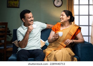 Happy smiling couple having tea or coffee while talking each other at home during morning - concept of family time, relaxation and refreshment - Powered by Shutterstock