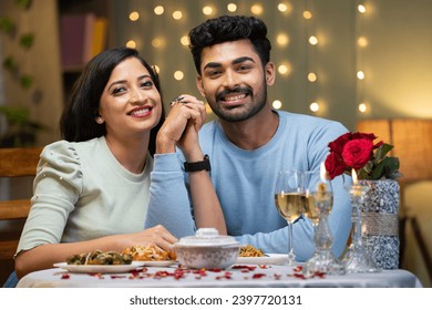 Happy smiling couple holding hands by looking at camera during candle light dinner at home - concept of valentine's day, love and relationship. - Powered by Shutterstock