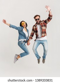 happy smiling couple isolated active jumping on white studio background, stylish man and woman in casual denim hipster outfit wearing shirt and sunglasses having fun together, dating friends - Shutterstock ID 1389203831