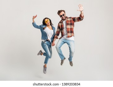 happy smiling couple isolated active jumping on white studio background, stylish mand and woman in casual denim hipster outfit wearing shirt and sunglasses having fun together, dating friends - Shutterstock ID 1389203834