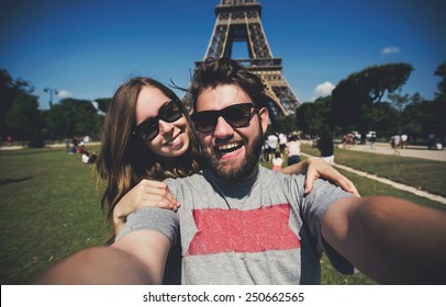Happy smiling couple kissing and taking selfie photo in front of Eiffel Tower in Paris while traveling across France - Powered by Shutterstock