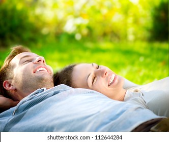 Happy Smiling Couple Relaxing on Green Grass.Park.Young Couple Lying on Grass Outdoor - Powered by Shutterstock