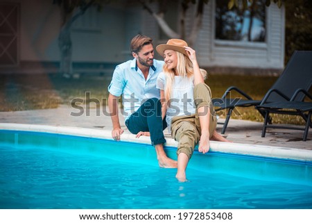 Happy smiling couple sitting by the pool.