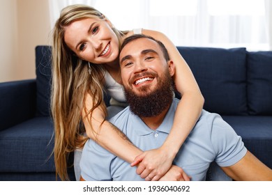 Happy smiling couple sitting on blue sofa in living room - Powered by Shutterstock