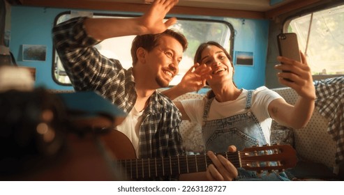 Happy Smiling Couple Taking a Selfie Photo for Family, Relatives or Friends. Having Funny Conversations on Video Call. Young Man and Woman Travelling in a Motorhome, Recording Video for Social Media - Powered by Shutterstock