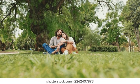 Happy smiling couple talking while sitting on blanket in park