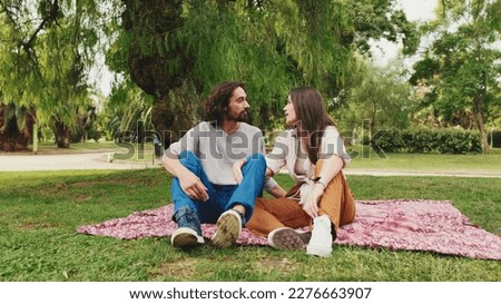 Happy smiling couple talking while sitting on blanket in park